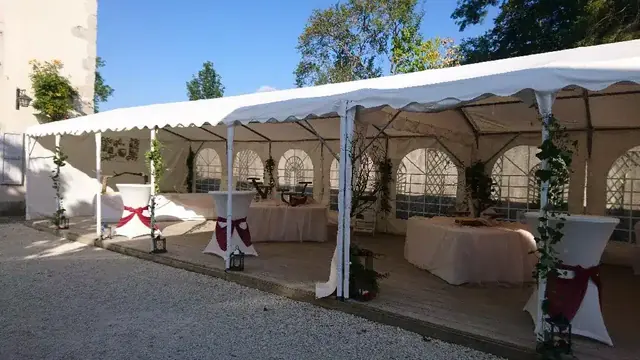 Chapiteau blanc aux fenêtres arrondies installé sur le gravier de la cour