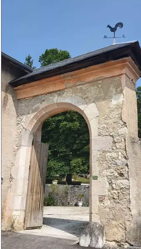 Porche d’entrée en pierre du domaine, surmonté d’un toit en tuiles