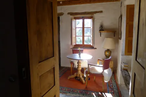 Chambre d’hôtes au mobilier ancien, table ronde devant une fenêtre à petits carreaux
